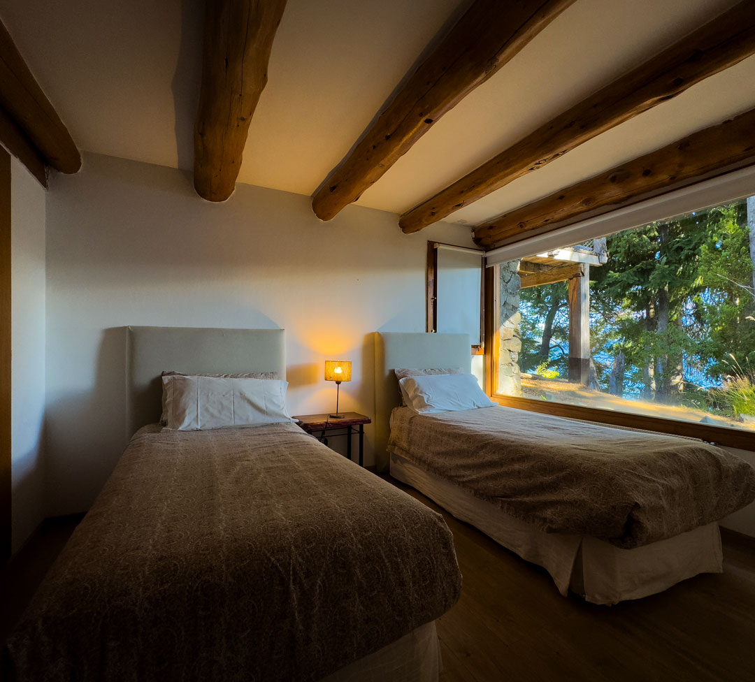 Dormitorio con dos camas y ventanal al bosque en la Cabaña Superior